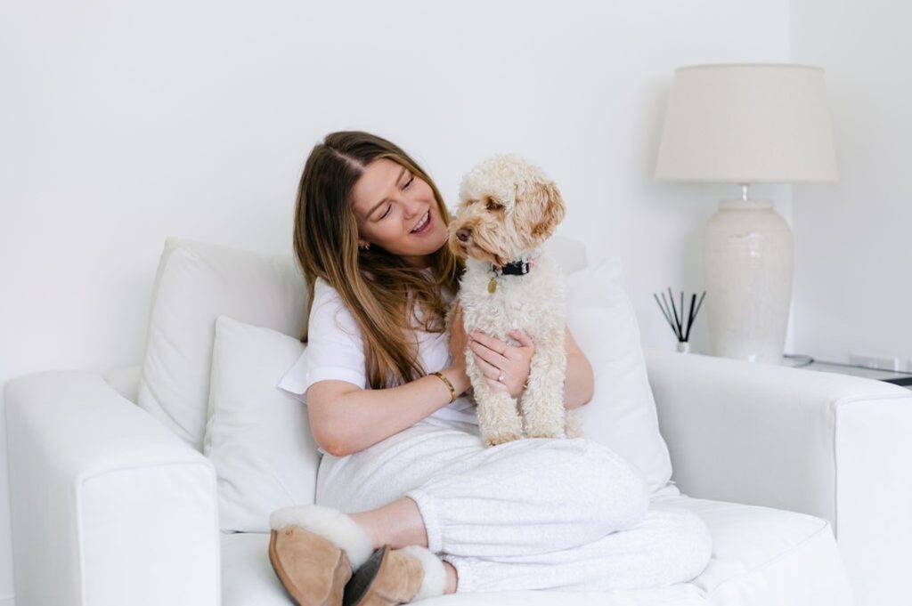 The Perfectionism Therapist, Natalie Englander, a woman sitting on a sofa with her dog, reflecting on what to do about perfectionism burnout.