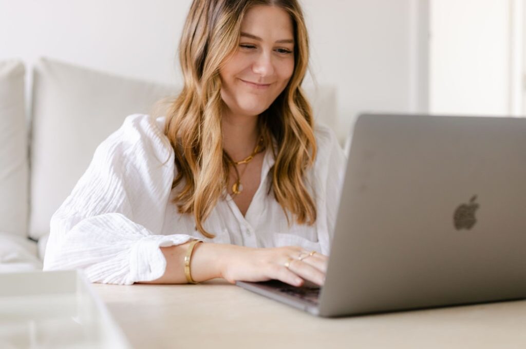 The Perfectionism Therapist, Natalie Englander, a woman typing on her laptop about why 'good enough' isn't good enough for perfectionists